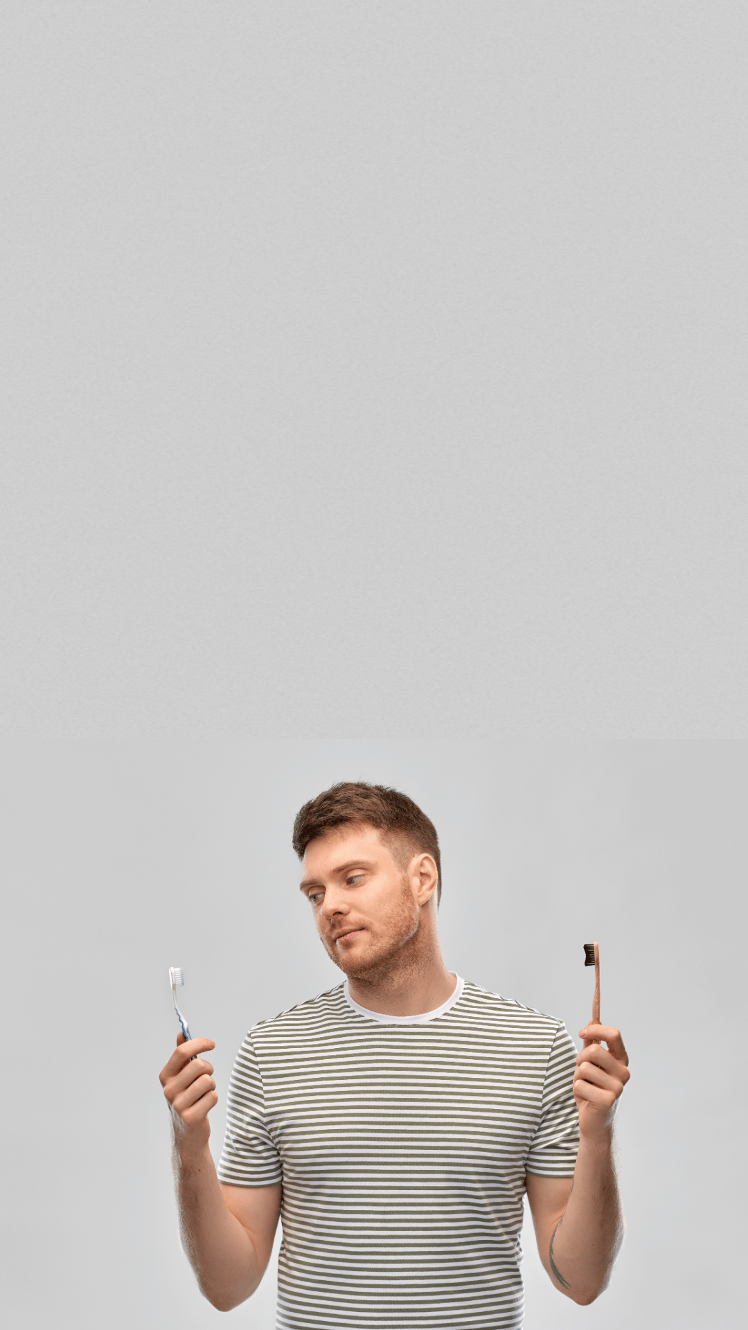 A man comparing bamboo toothbrush with plastic toothbrush